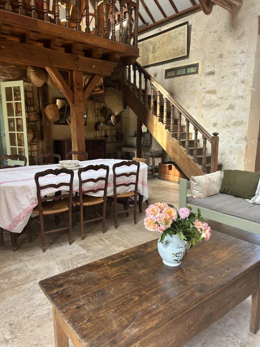L’intérieur de la grange de pierre, son escalier de bois, sa longue table et sa cheminée