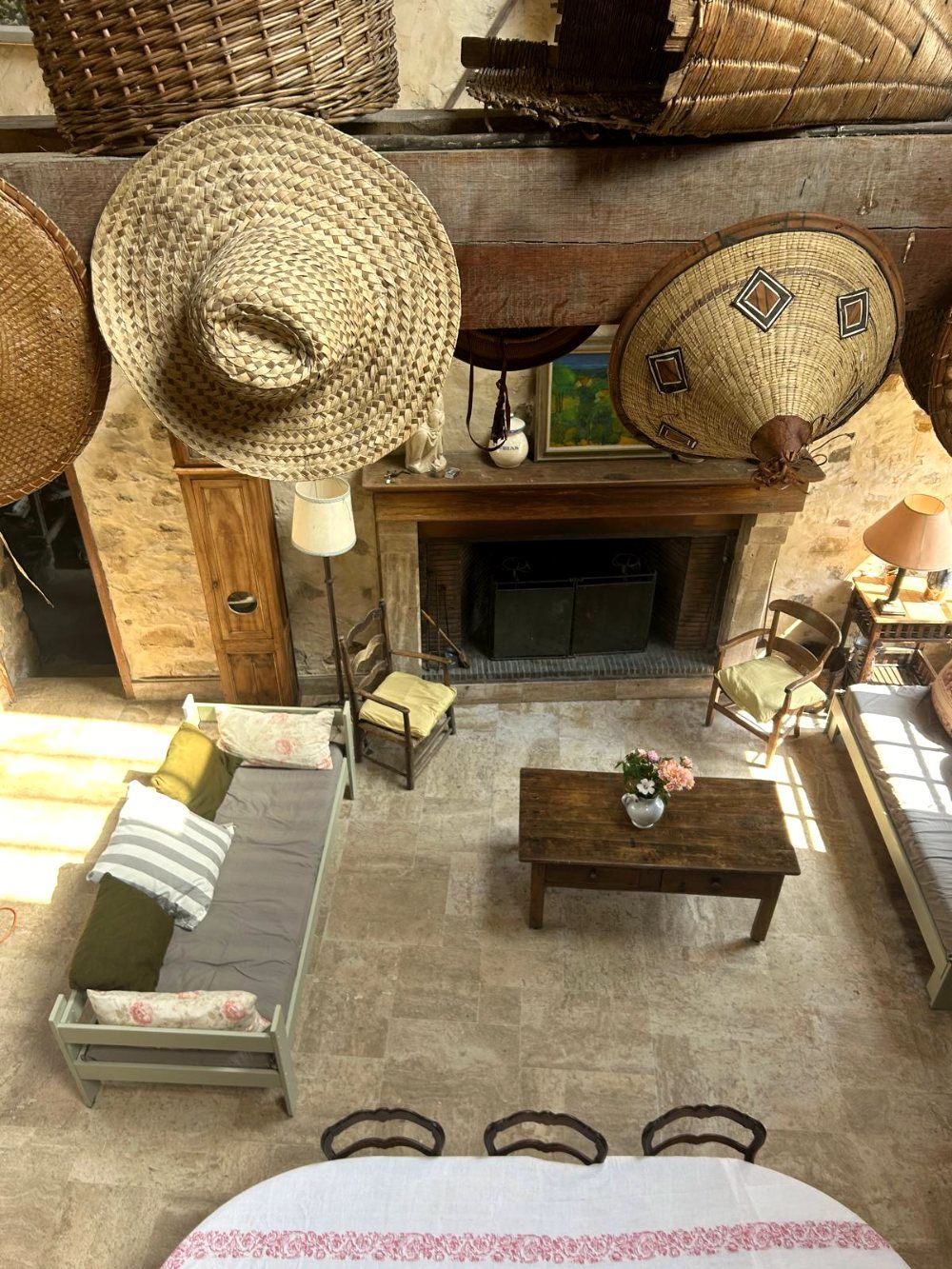 Vue depuis la mezzanine sur la grange, sa cheminée et les chapeaux tressés sur la poutre